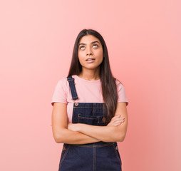 Young pretty arab woman wearing a jeans dungaree tired of a repetitive task.