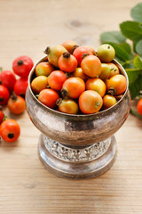 Vintage striped box of rose hip fruits on wooden table.