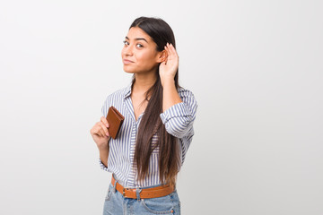 Fototapeta premium Young arab woman holding a wallet trying to listening a gossip.