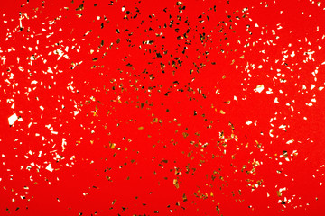 Golden falling confetti on red background.