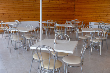 Chromed tables and chairs against the background of a wall made of wood.
