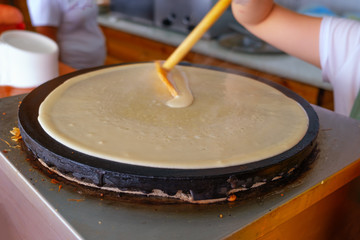 The process of making pancakes. The dough spreads over the hob. Selective focus.