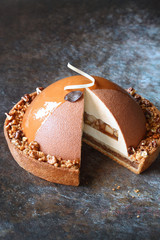 Contemporary Caramel, Walnut, Apple Cake Tart, covered with velvet spray and caramel glaze, on dark background.