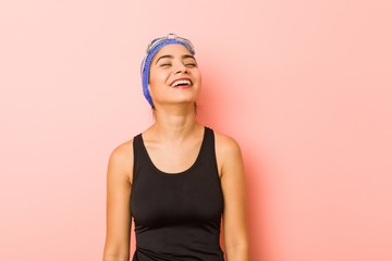 Young arab swimmer woman isolated relaxed and happy laughing, neck stretched showing teeth.