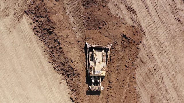 Bulldozer pushing large amount of fresh soil, Aerial follow footage.