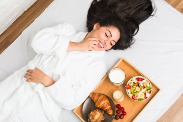 Obraz na płótnie Canvas Young hispanic woman having breakfast on the bed