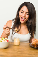 Young hispanic woman having breakfast on the table