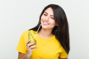 Young hispanic woman drinking a pear juice with a straw