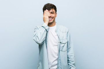 Young hispanic cool man having fun covering half of face with palm.
