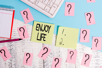 Conceptual hand writing showing Enjoy Life. Concept meaning Any thing, place,food or demonstrating, that makes you relax and happy Writing tools and scribbled paper on top of the wooden table