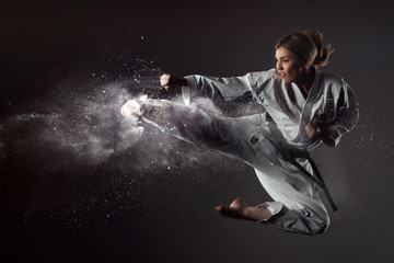 Fototapeta na wymiar Karate girl bounces and makes a kick