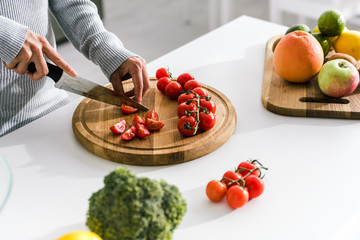 selective focus of woman holding knife near cherry tomatoes