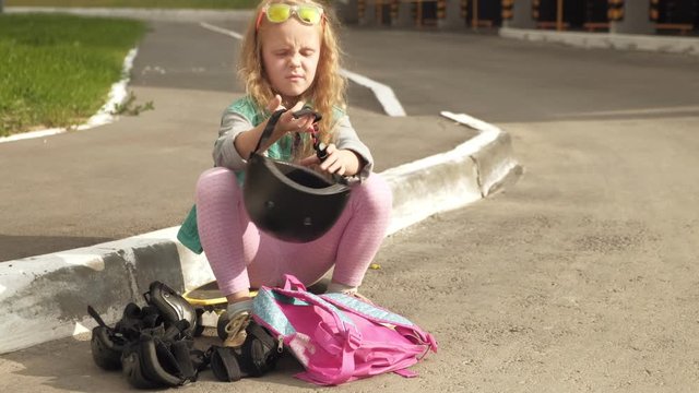 Little girl dresses protection: helmet, knee pads and elbow pads. Sunset