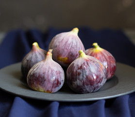 Purple figs on black plate, dark background, closeup