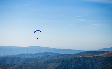 Fototapeta na wymiar Paraglider flying over mountains peak in autumn day with beautiful aerial world view. Freedom lifestyle concept