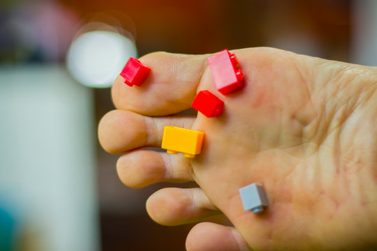 A Man Foot Step On Colored Toy Brick On Ground And Pain Full.