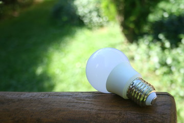 LED bulb on the wooden table and lighting of sub lay with green nature background for eco saving...