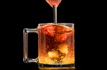 making black tea from a bag with sugar in motion on a black background