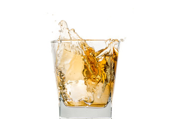 glass of whiskey with ice and a splash and spray from falling on a white background
