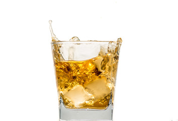 glass of whiskey with ice and a splash and spray from falling on a white background