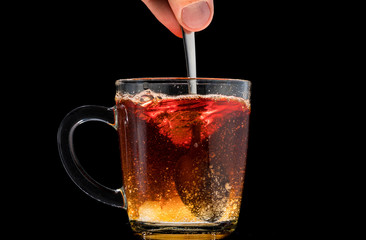 making black tea from a bag with sugar in motion on a black background