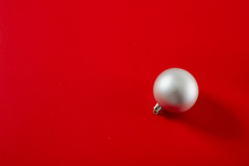 Silver  Christmas Ball on red background flat lay