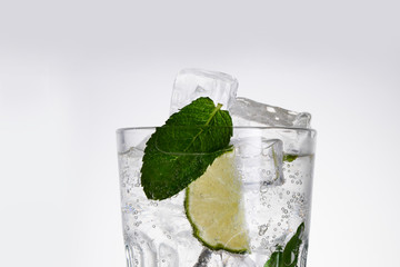 Glass of lemonade with lemon, lime and mint on white background.  Soda water with citrus and ice. Lime and orange in sparkling water