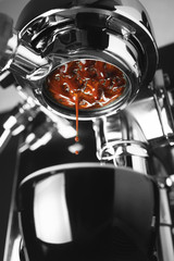 A coffee machine is preparing a cup of espresso. Blurred background.