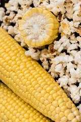 Raw corn cobs and popcorn close up.