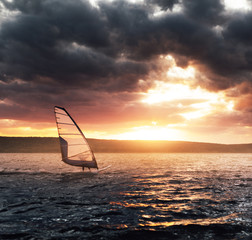 Windsurfing on a lake at sunset.