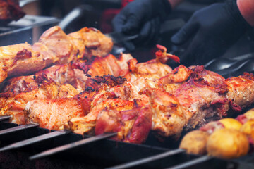 Man in black gloves fries meat on the grill, picnic. Cooking barbecue on the grill. Barbecue with meat on skewers