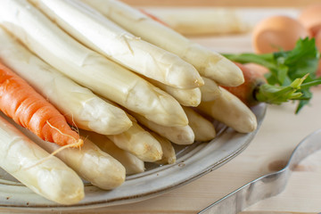 Fototapeta na wymiar New harvest of white asparagus, high quality raw asparagus, carrot and selery in spring season, ready to cook