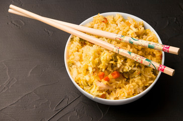 plate with rice and chopsticks on a black background. Rice dish