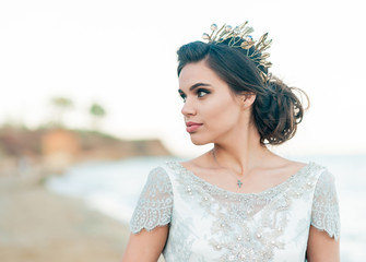 Closeup portrait of pretty bride in luxury wedding dress with bouquet at the sea side. Wedding by the sea. Bride walking around the sea near the place of the wedding ceremony. © trofalena
