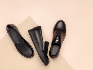Black leather shoes no laces on beige and pink pastel background