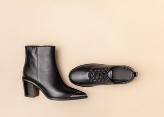 Black ankle boots and boots on beige pastel background