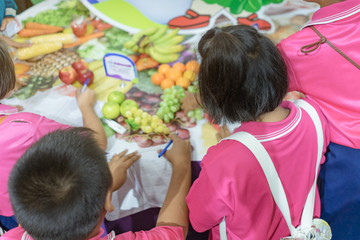 Primary school girls learn and take notes about different types of fruits at school.