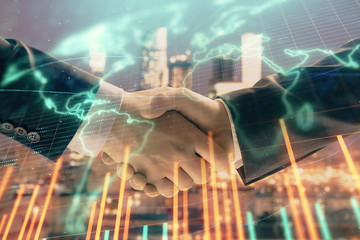 Double exposure of financial chart and world map on cityscape background with two businessmen handshake. Concept of international investment