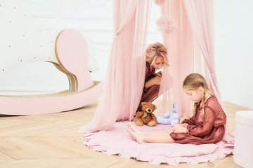 Obraz na płótnie Canvas Cute little girl plays with a bear in toy house
