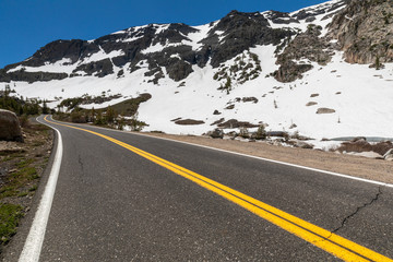 Low angle view of a road snaking to the horizon in a snow-covered mountain environment