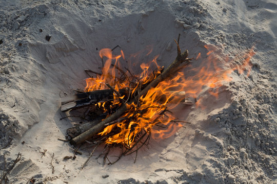 Small Bonfire Burning on Sandy Beach with Orange Flames