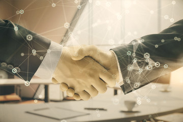 Multi exposure of tech theme hologram on office background with two men handshake. Concept of technology