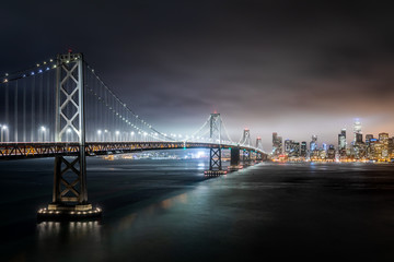 Night shot of San Francisco skyline, with the Bay Bridge in the foreground and skyscrapers in the background
