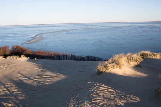 Golden Hour Light on Coastal Sand Dunes and Calm Sea