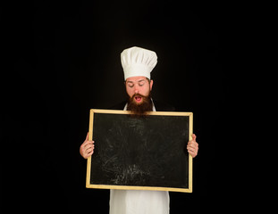 Restaurant chef show empty chalkboard. Advertising chef menu. Blank chalkboard with copy space for text. Male chef, cook or baker with blank board. Bearded chef holds blackboard. Business lunch menu.