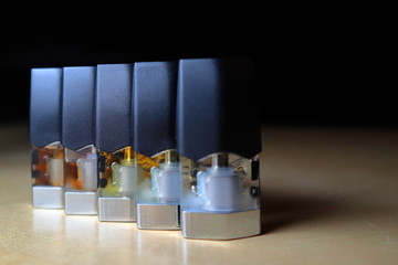 e-juice vape refill pods with liquids of different shades of orange arranged to form a gradient, isolated close up