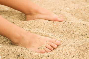Female legs in the sand. Human foot. Sea. Advertising