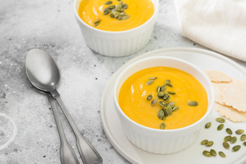 Autumn pumpkin cream soup with seeds. Light grey background