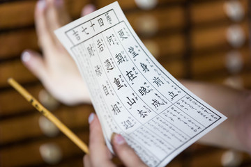 Close up of female hands holding a fortune-telling note against a bokeh background