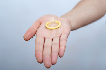 Fototapeta na wymiar Woman hand holds a condom. Contraceptives, sexually transmitted diseases